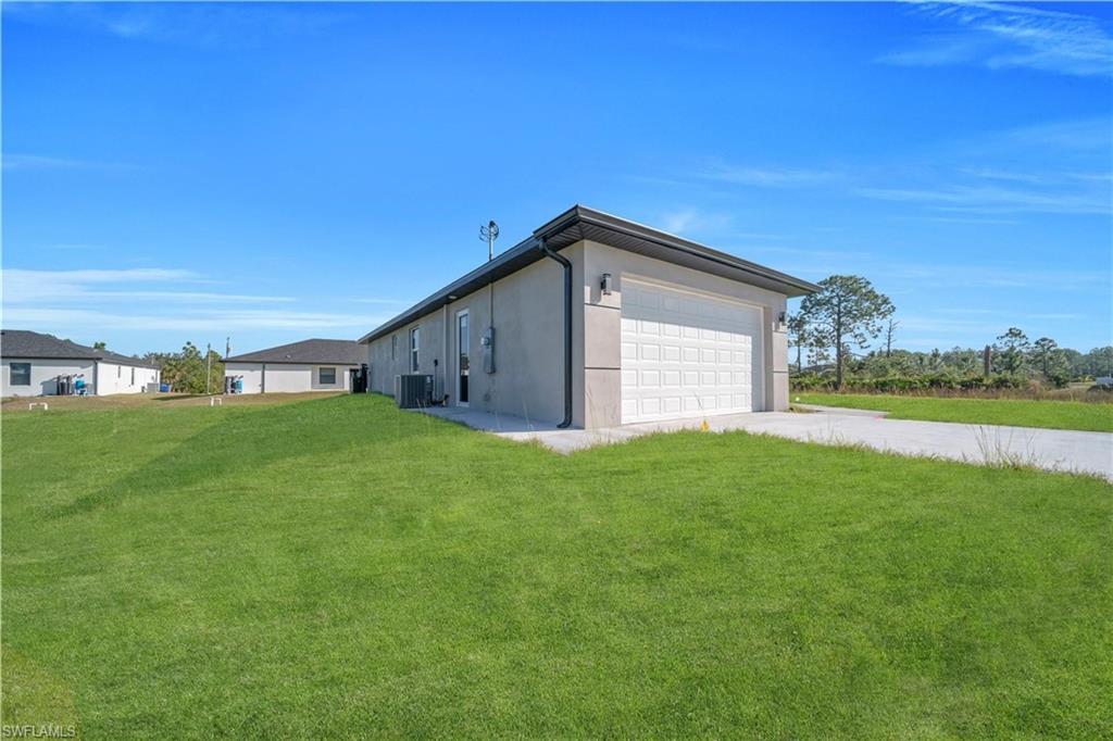 View of home's exterior with a yard, stucco siding, driveway, and a garage
