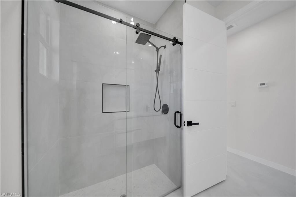 Full bath with a shower stall and concrete flooring