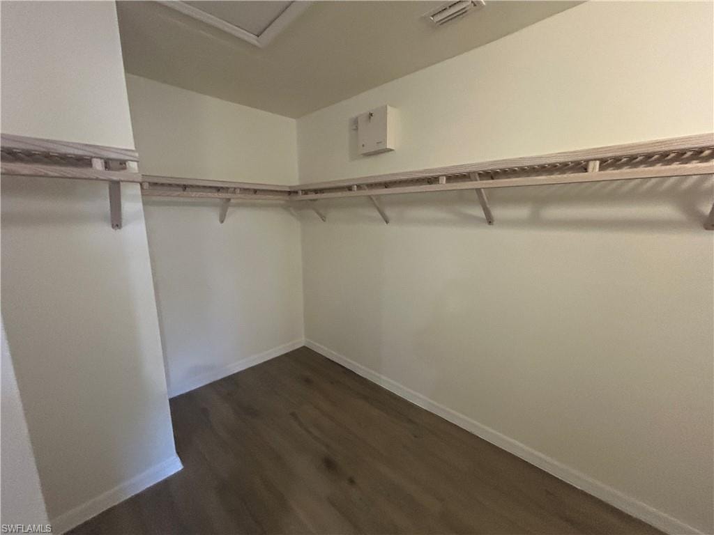 Walk in closet featuring dark wood-style floors and attic access