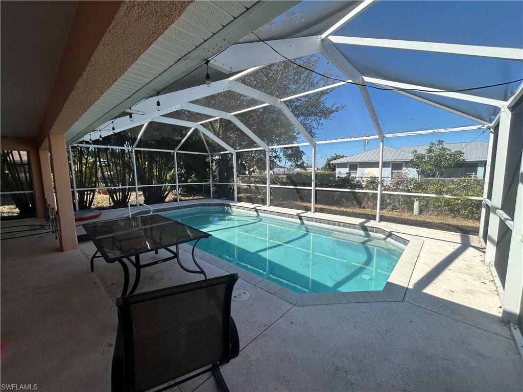 Swimming pool with a sunroom, a patio area, and glass enclosure