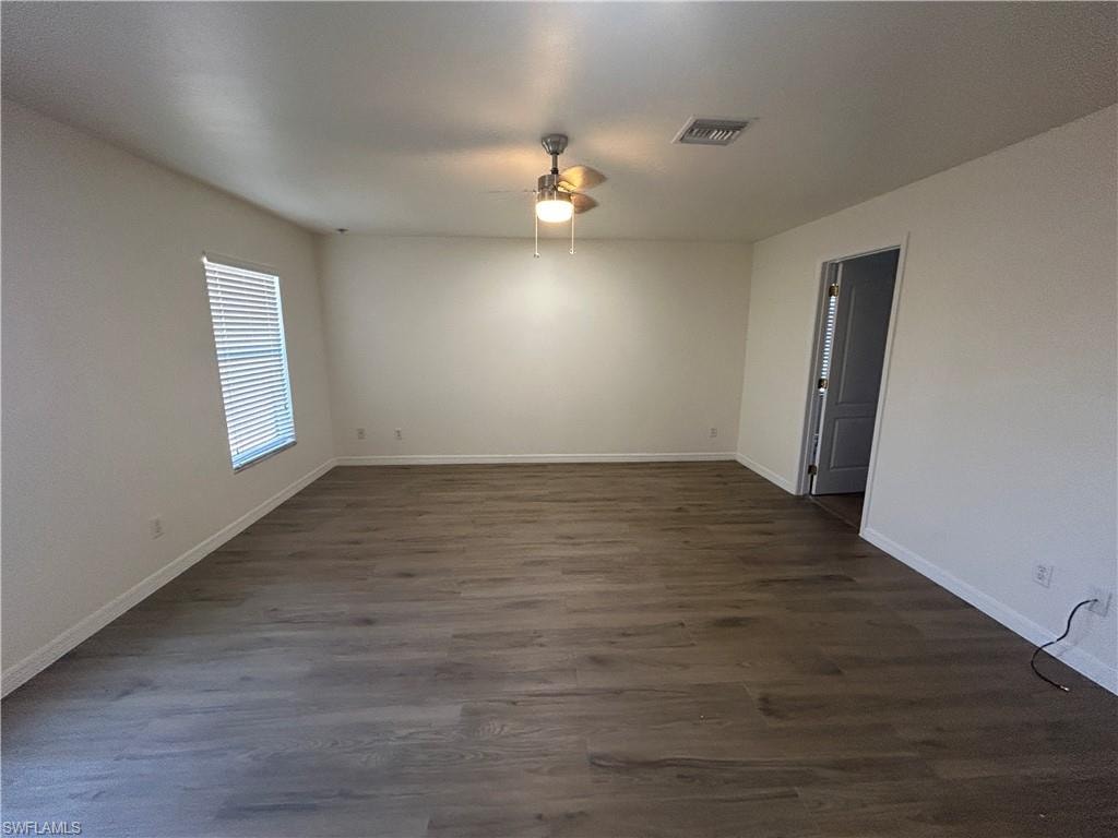 Spare room featuring dark wood-type flooring and ceiling fan