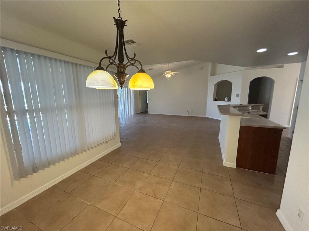 Unfurnished dining area featuring arched walkways, light tile patterned flooring, vaulted ceiling, ceiling fan, and recessed lighting