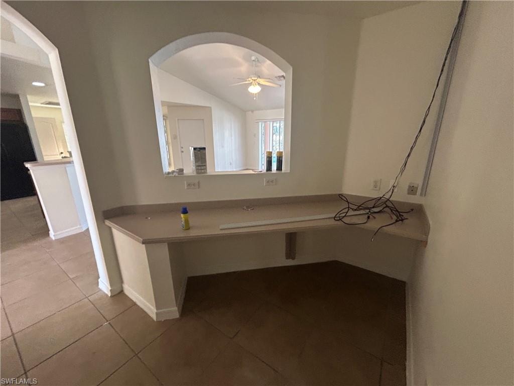 Kitchen with lofted ceiling, a ceiling fan, dark tile patterned floors, and arched walkways