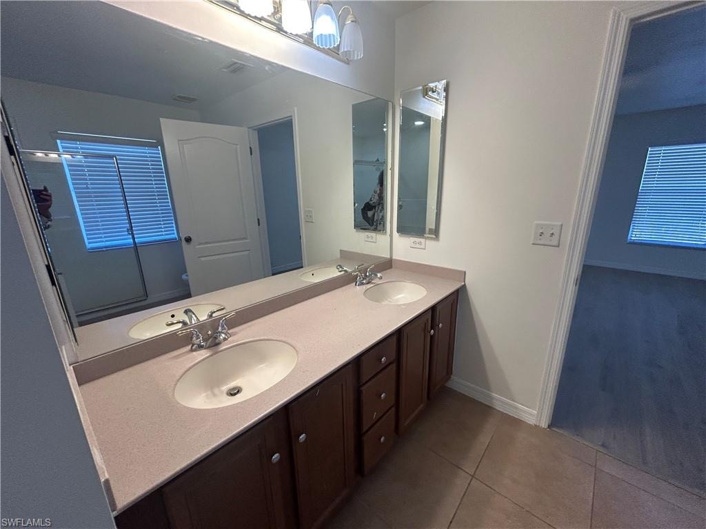 Bathroom featuring double vanity and dark tile patterned floors