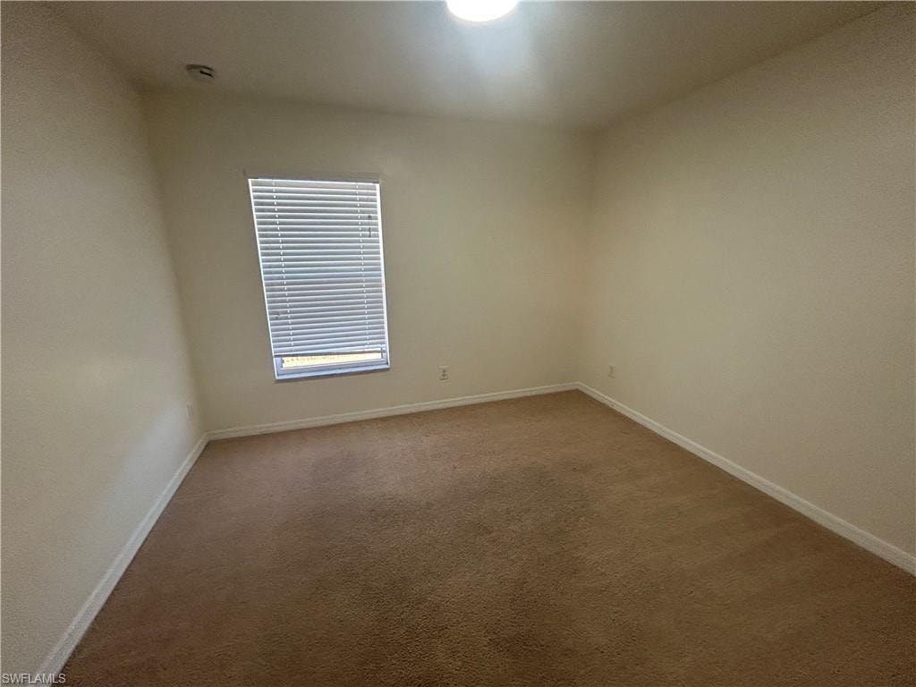 Spare room featuring carpet flooring and baseboards