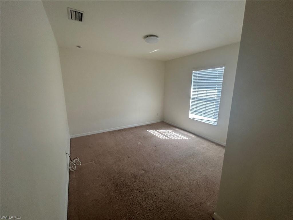 Carpeted empty room featuring baseboards