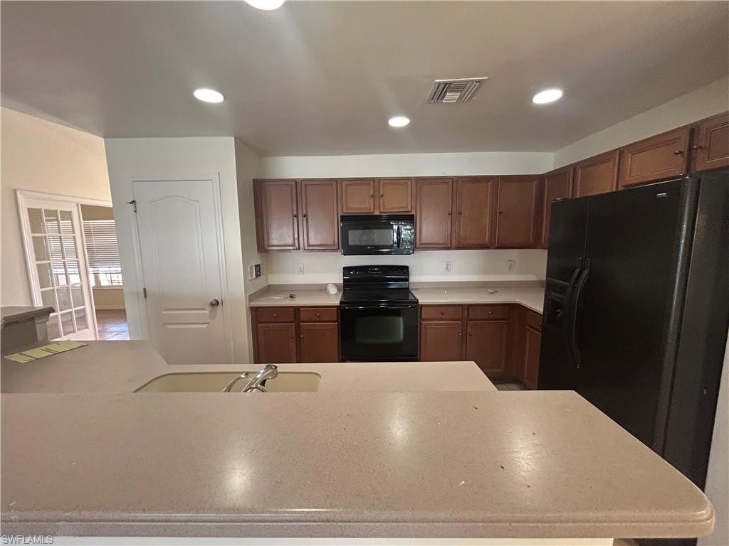Kitchen featuring black appliances, recessed lighting, and light stone counters