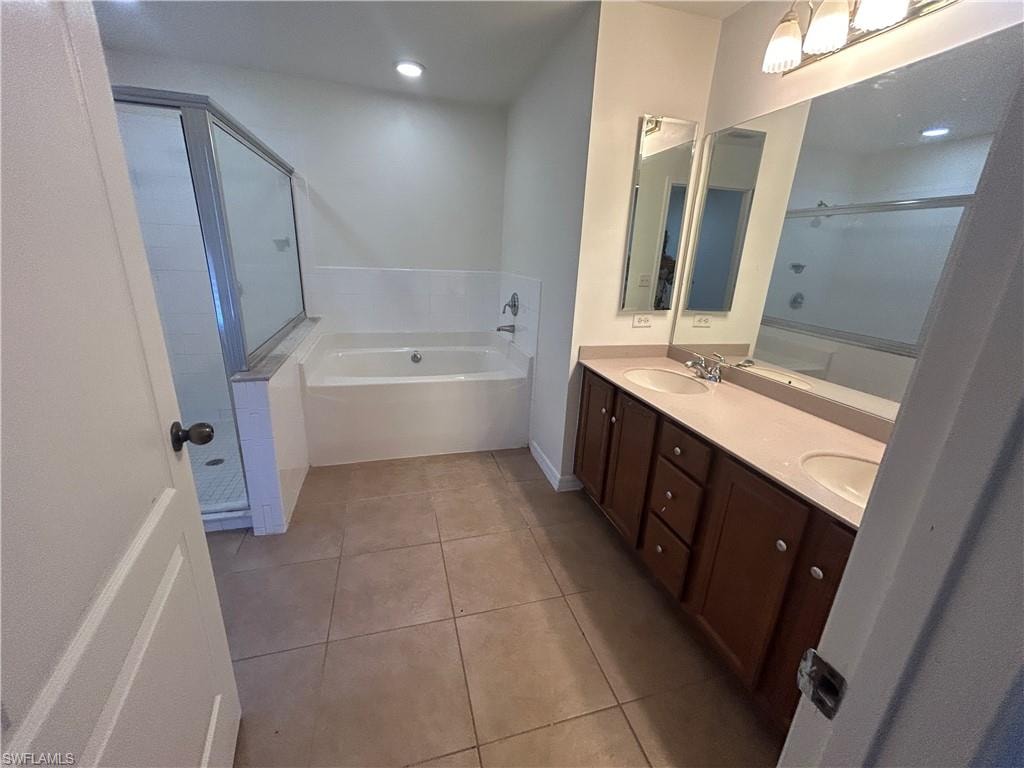 Bathroom featuring a garden tub, double vanity, light tile patterned flooring, and a stall shower