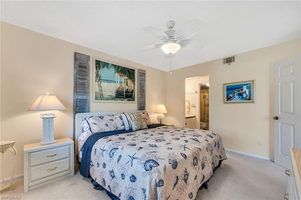 Bedroom with light colored carpet, a ceiling fan, and connected bathroom