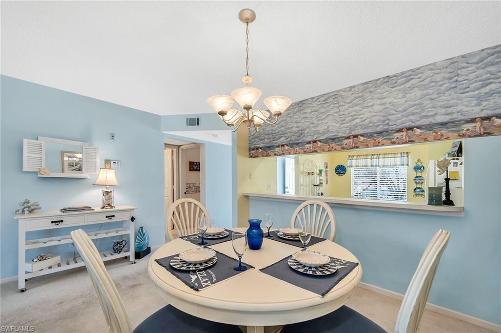Carpeted dining space featuring suspended lighting and baseboards
