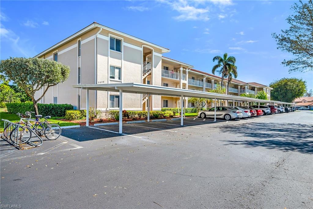 View of apartment building / complex featuring covered parking