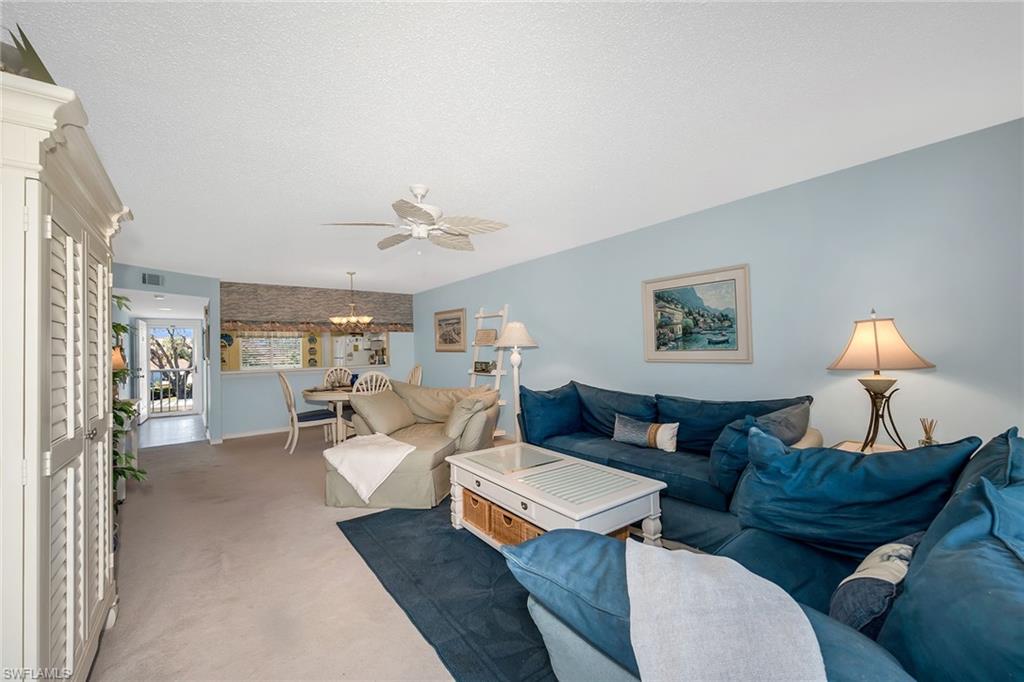 Living area with carpet floors, ceiling fan, a textured ceiling, and suspended lighting