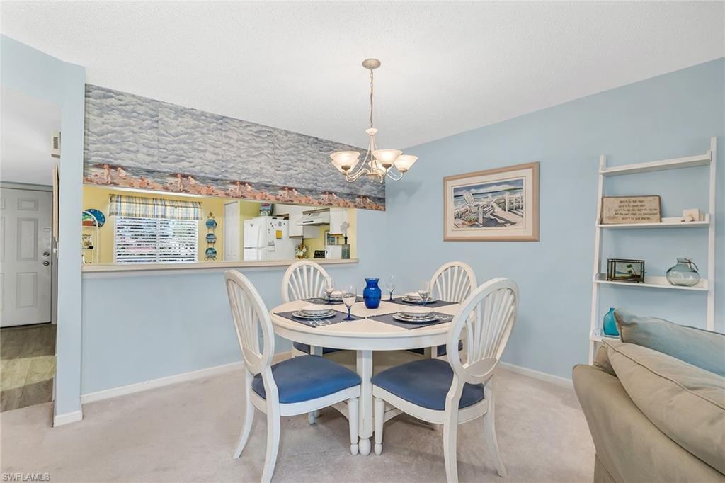 Carpeted dining room with a chandelier and baseboards