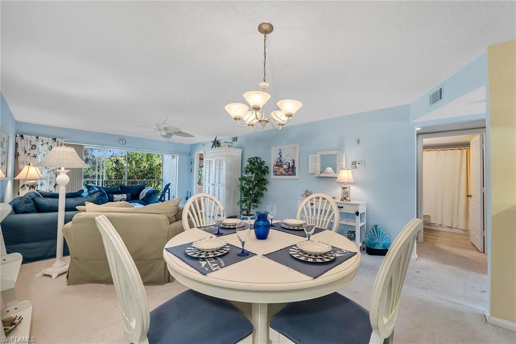 Carpeted dining space featuring hanging lights and ceiling fan