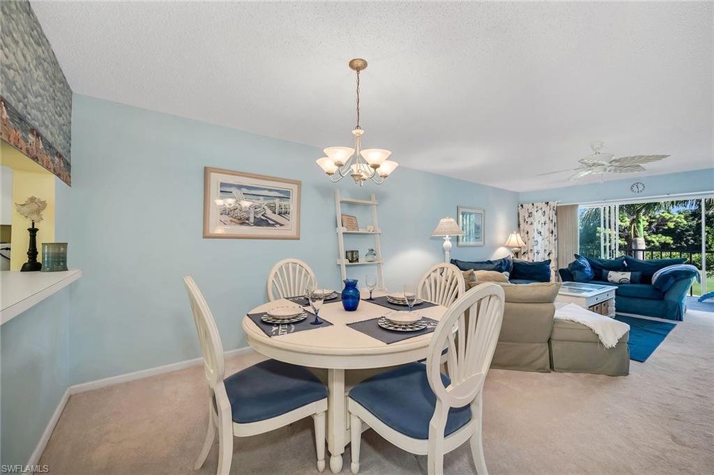 Dining room featuring carpet, suspended lighting, ceiling fan, and a textured ceiling