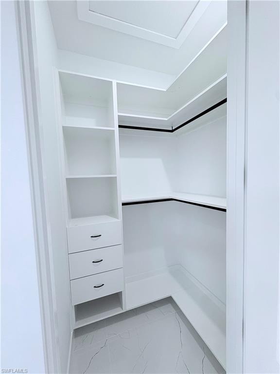 Walk in closet with light marble finish floors