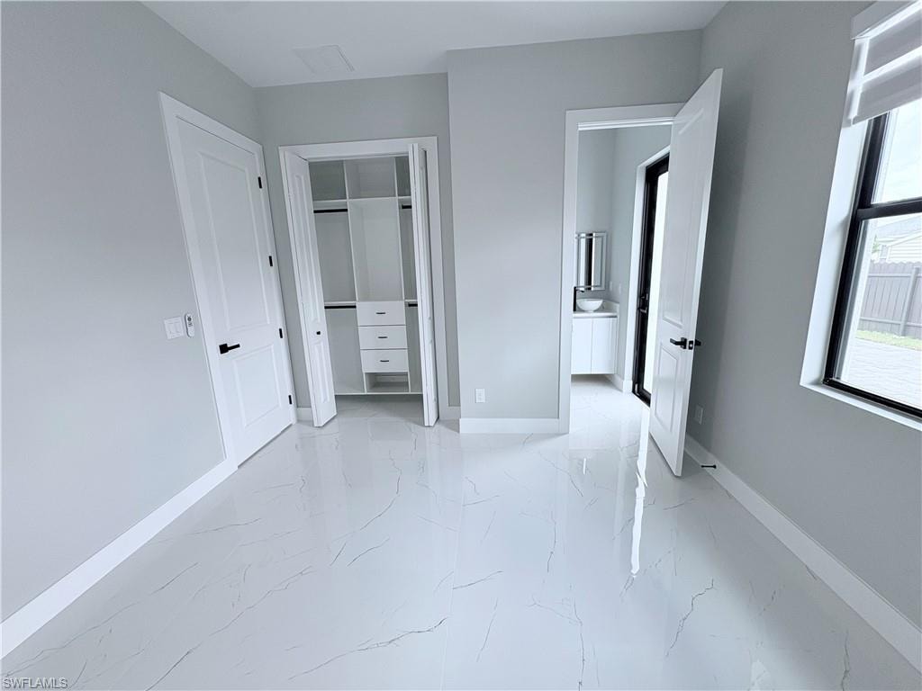 Unfurnished bedroom with light marble finish floors and a closet