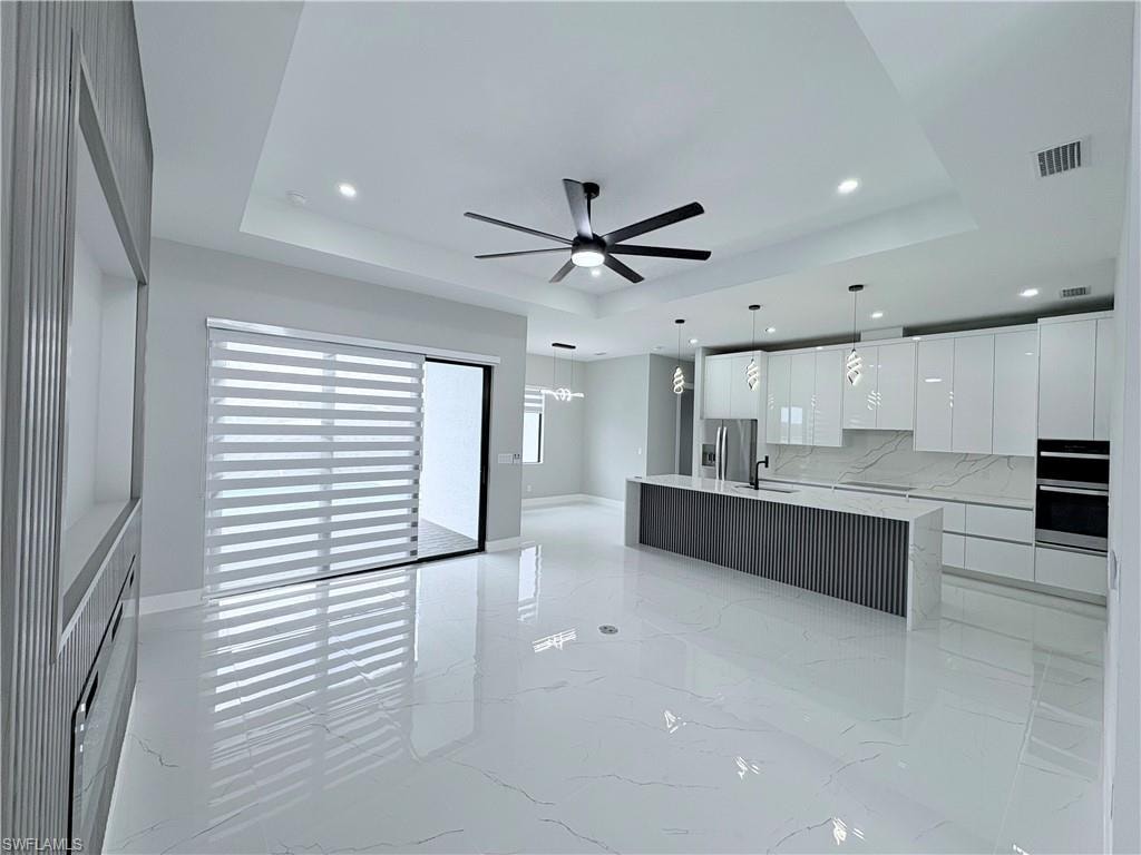 Kitchen with modern cabinets, white cabinetry, ceiling fan, a large island, and tasteful backsplash