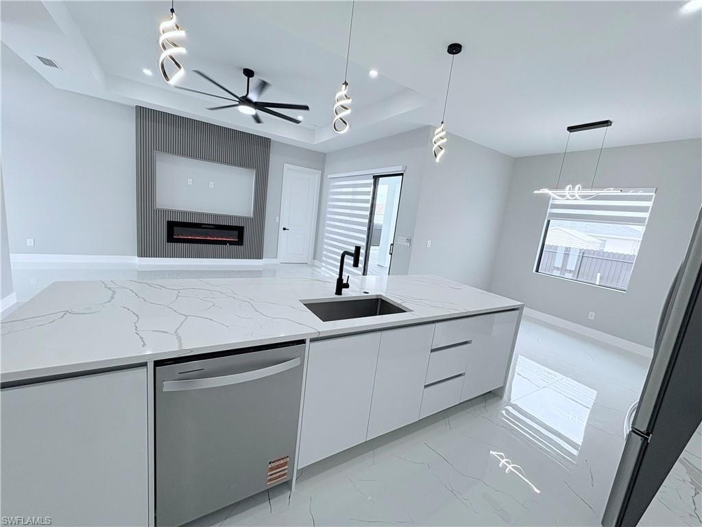 Kitchen with light stone counters, modern cabinets, white cabinets, stainless steel appliances, and a raised ceiling