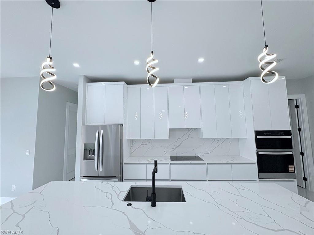 Kitchen featuring pendant lighting, stainless steel appliances, and light stone counters