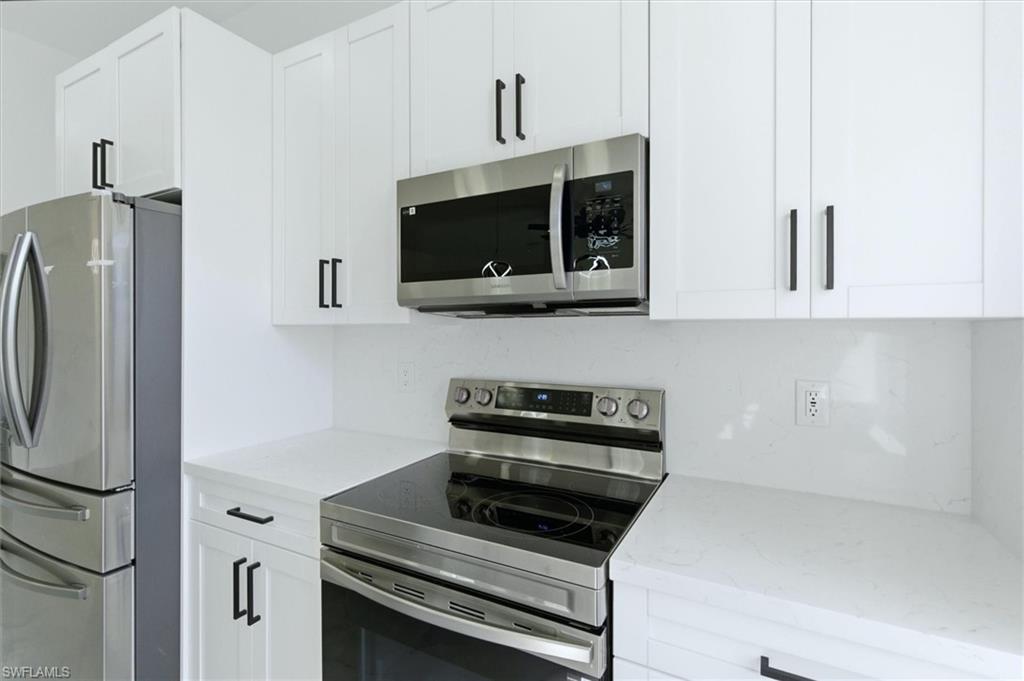 Kitchen featuring stainless steel appliances, light stone countertops, and white cabinetry
