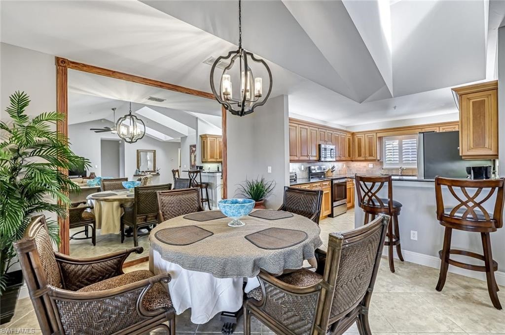 Dining area with vaulted ceiling, hanging lights, and light tile patterned flooring
