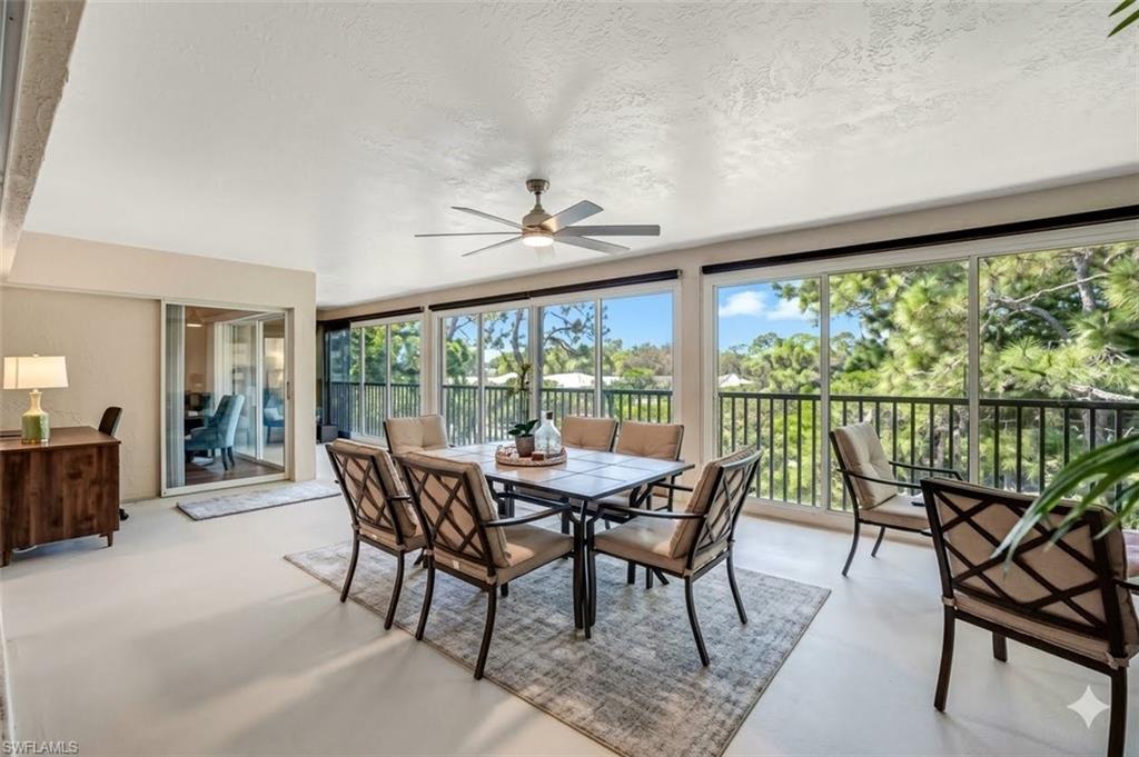 Expansive enclosed Lanai featuring a ceiling fan, sliding impact doors, a large window line, and a balcony railing