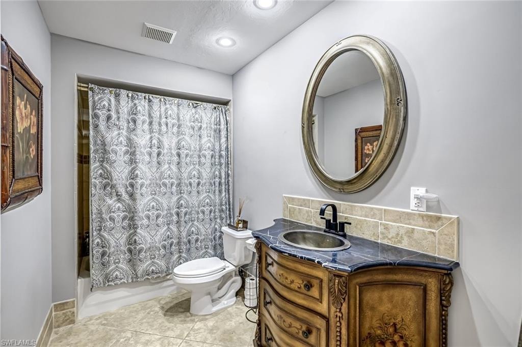 Full bath with vanity, light tile patterned flooring, and shower / bath combination