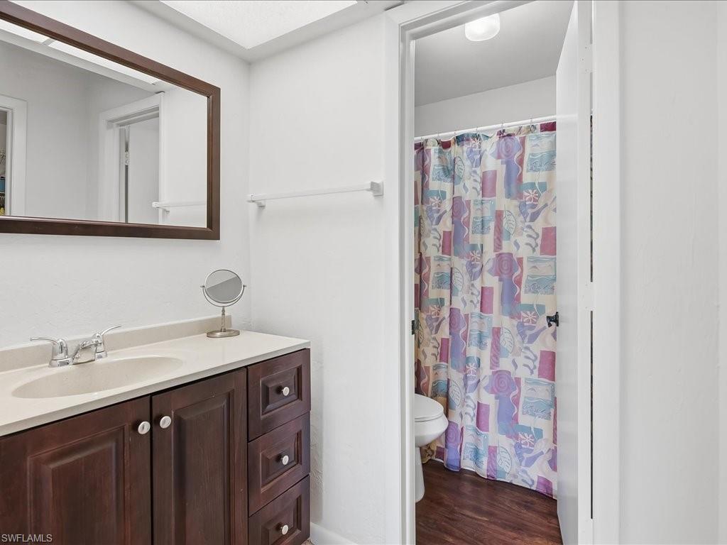 Bathroom featuring vanity, curtained shower, and dark wood-type flooring