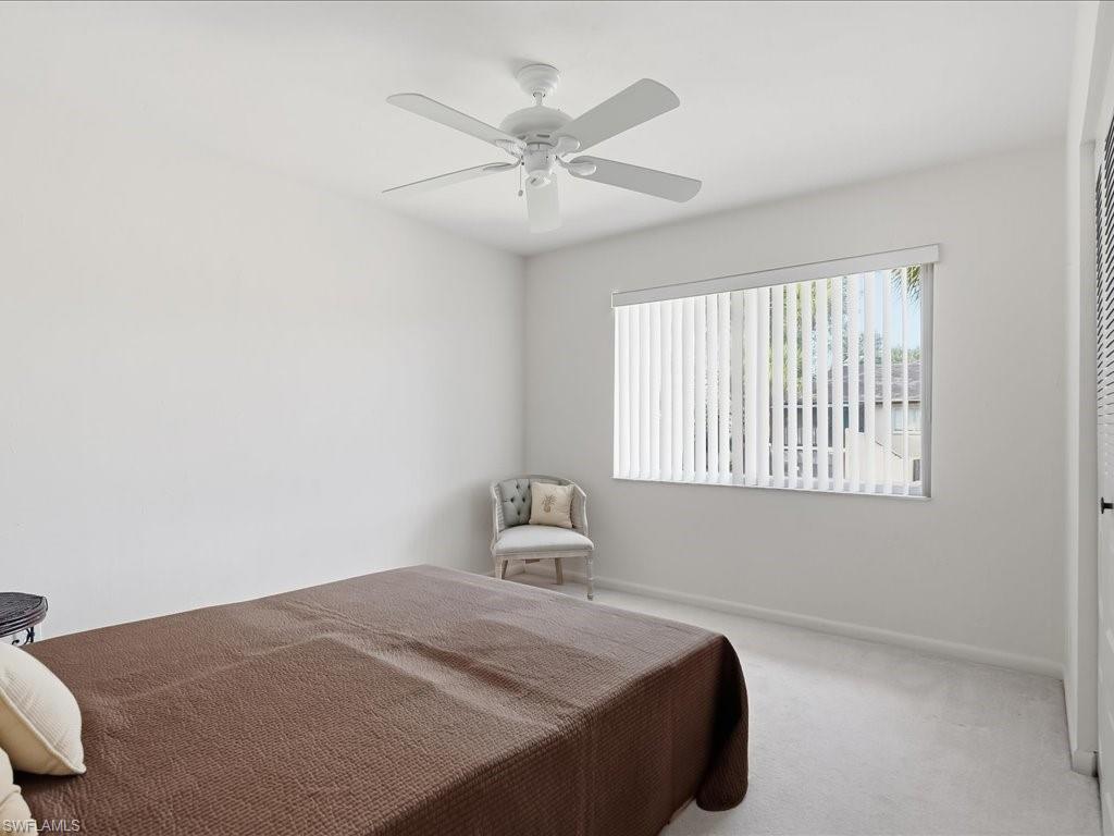 Carpeted bedroom with ceiling fan and baseboards