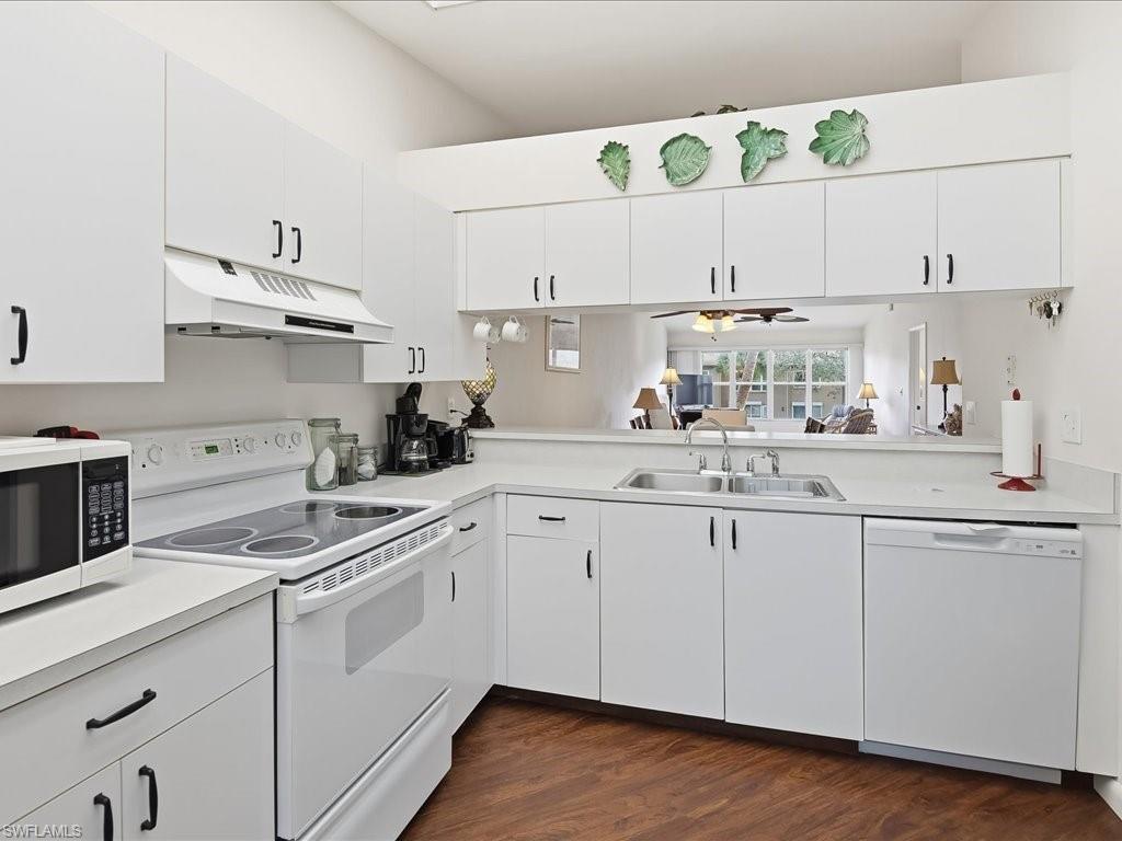 Kitchen featuring white cabinetry, white appliances, light countertops, under cabinet range hood, and a ceiling fan
