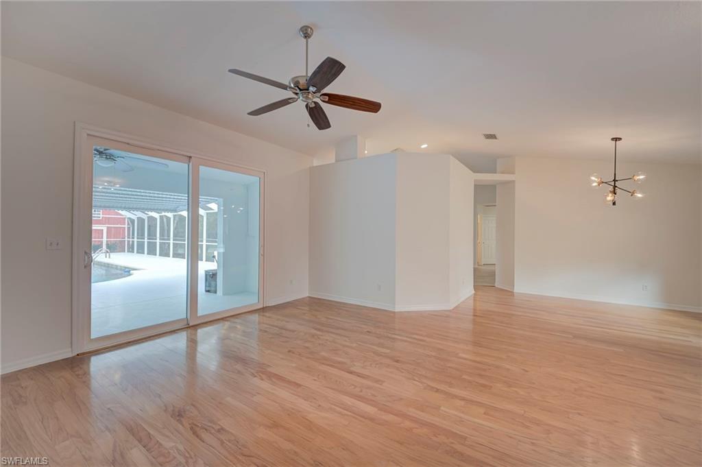 Spare room featuring lofted ceiling, light wood finished floors, hanging lights, and a ceiling fan