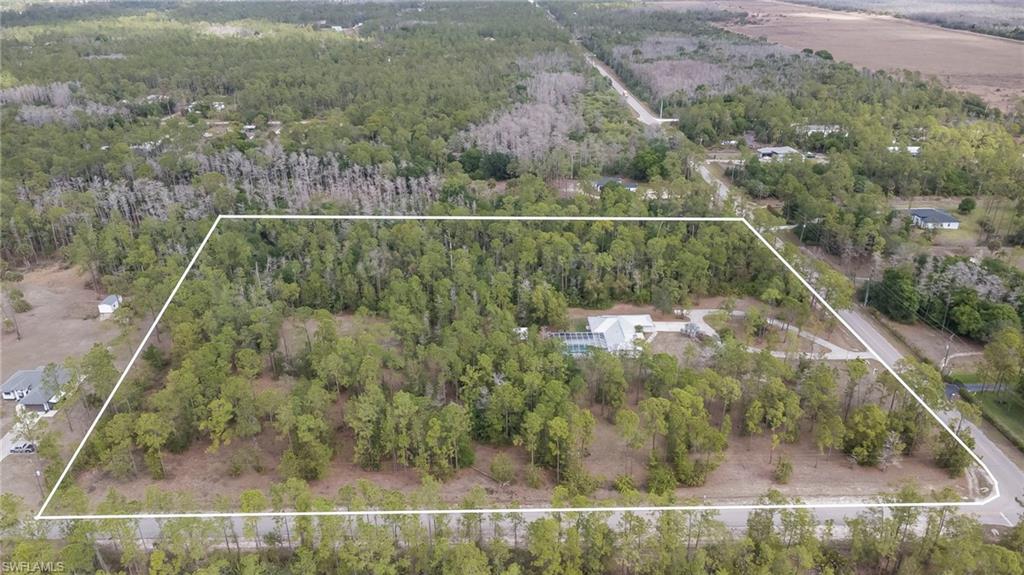 Aerial view of property and surrounding area featuring a forest and property parcel outlined