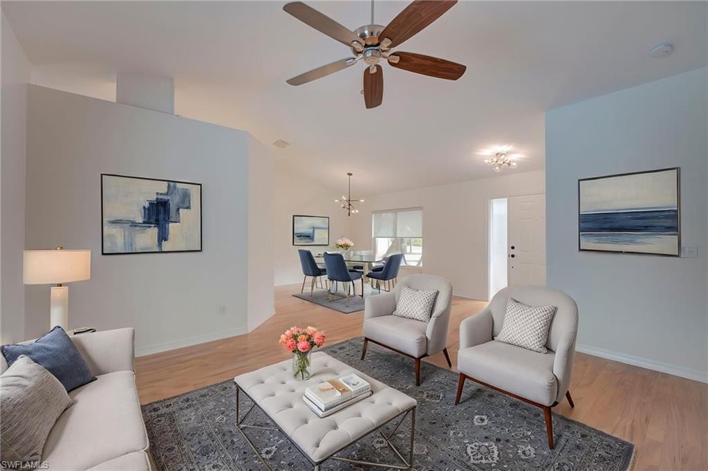 Living area featuring light wood finished floors, a ceiling fan, vaulted ceiling, and hanging lights