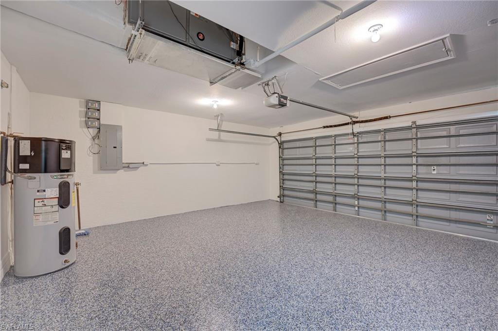 Garage with hybrid water heater, electric panel, and a garage door opener