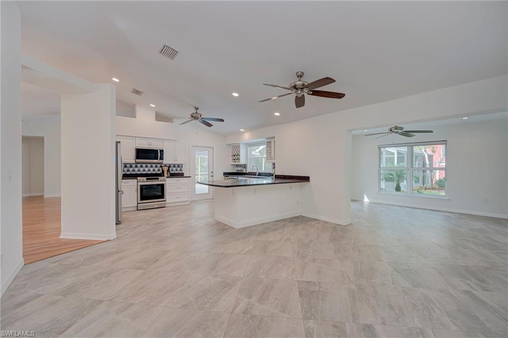 Kitchen with open floor plan, white cabinetry, dark countertops, stainless steel appliances, and a peninsula