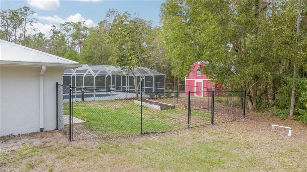 View of yard with a gate, an outdoor structure, glass enclosure, an outdoor pool, and a vegetable garden