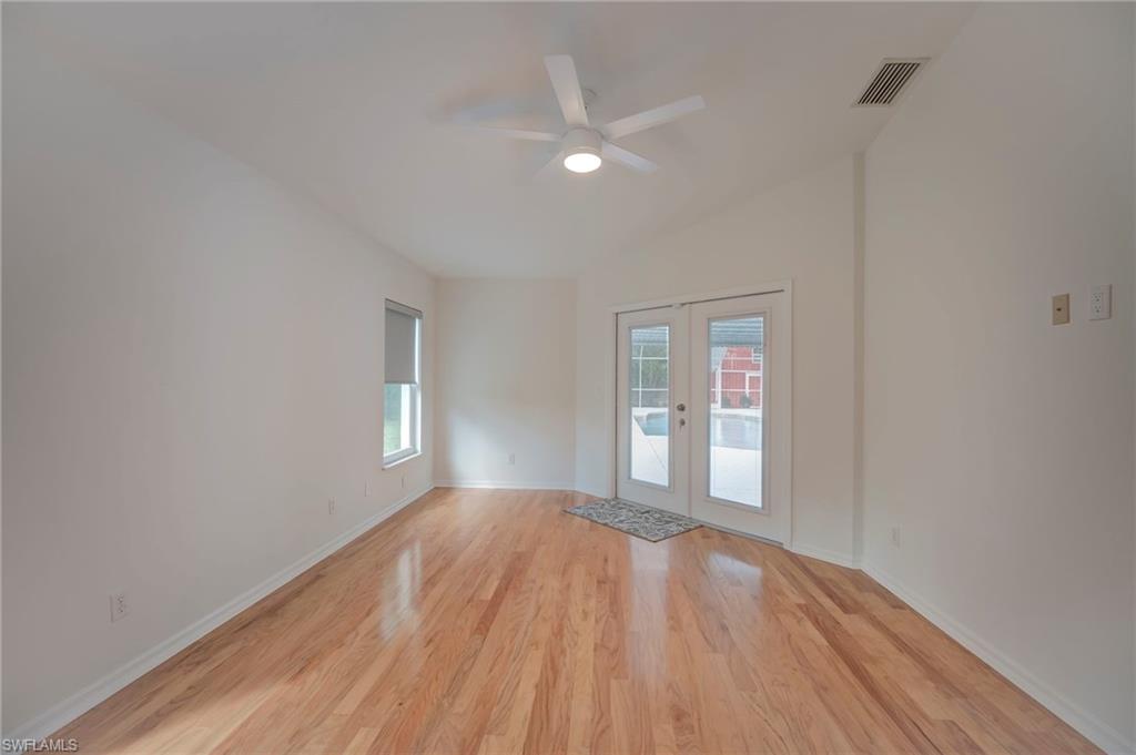 Spare room with french doors, light wood-style flooring, a ceiling fan, and plenty of natural light