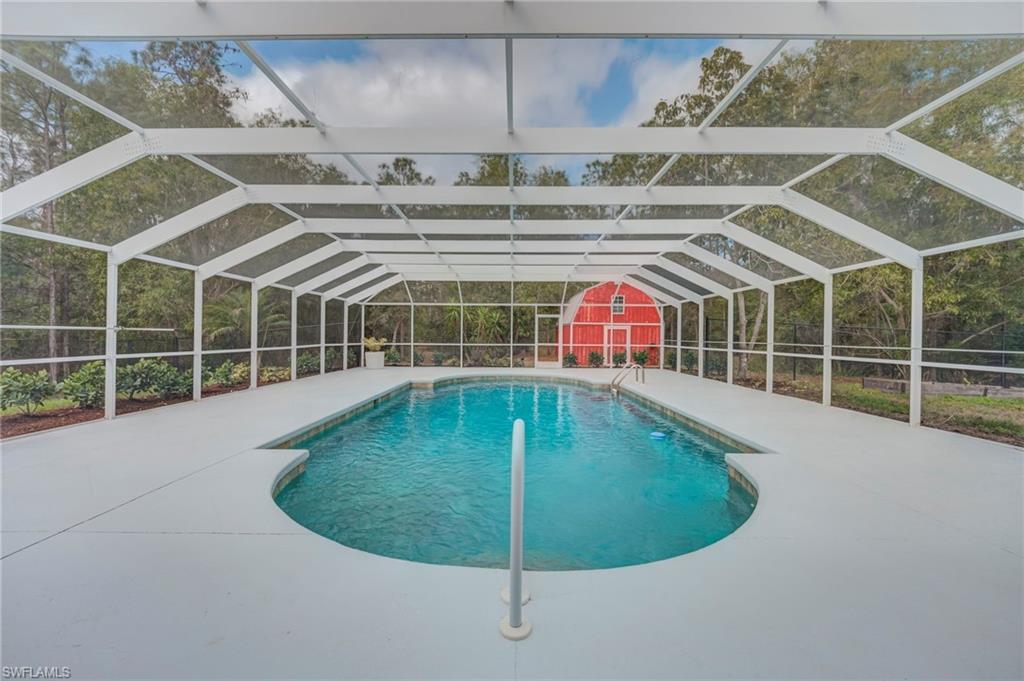 Swimming pool with glass enclosure, a sunroom, and a fenced backyard