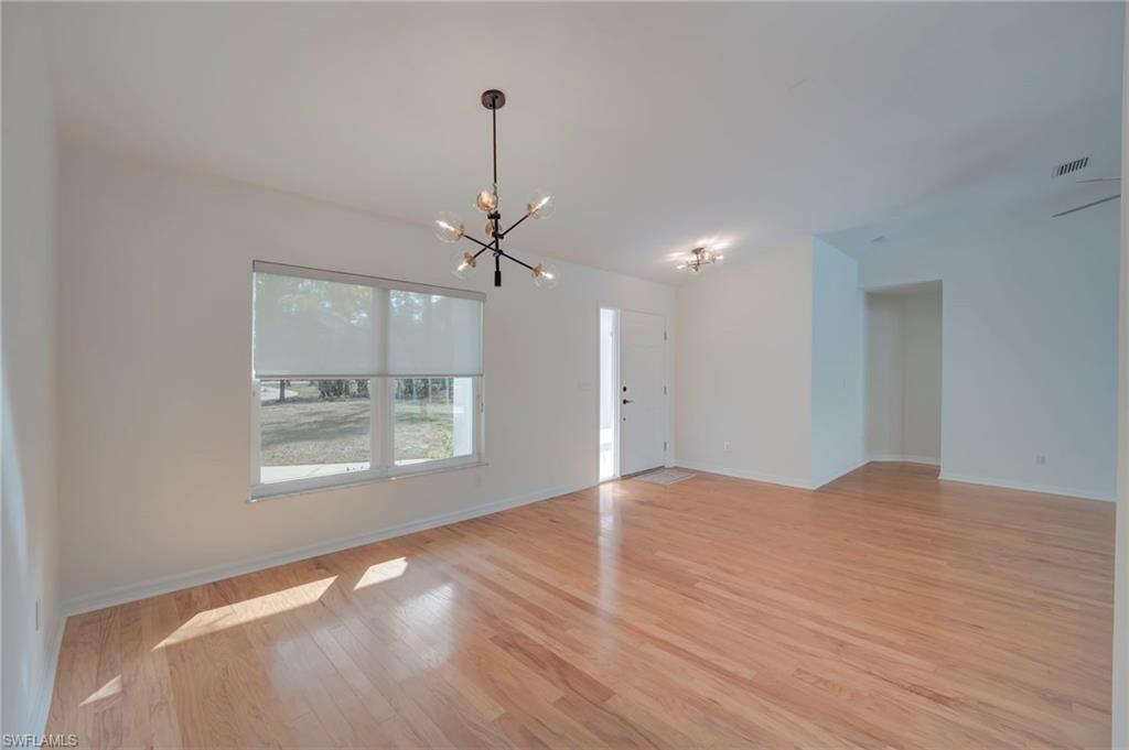 Unfurnished room with suspended lighting and light wood finished floors