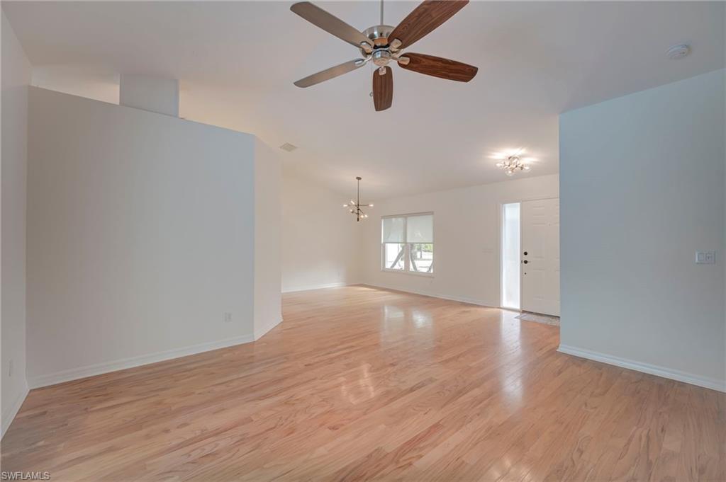 Spare room featuring suspended lighting, light wood-style flooring, and ceiling fan