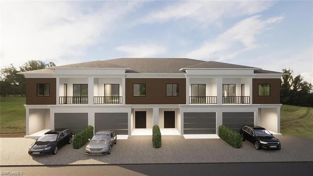 Rear view of property with a balcony, an attached garage, and driveway