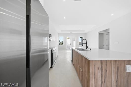 Two tone kitchen with stainless steel appliances, dual tone cabinets, a large island with sink, modern cabinets, and recessed lighting