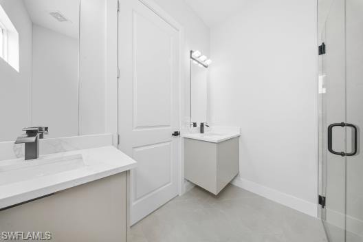 Bathroom featuring two vanities, a shower stall, and concrete floors