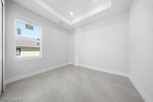 Unfurnished room with concrete floors, a tray ceiling, and recessed lighting