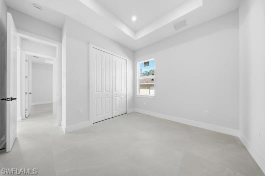 Unfurnished bedroom with a raised ceiling, a closet, and recessed lighting