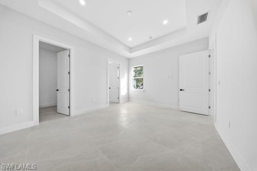 Unfurnished bedroom with a tray ceiling, concrete flooring, and recessed lighting
