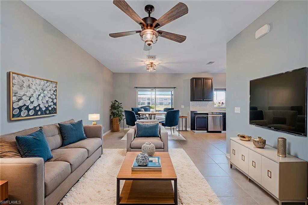 Living room featuring a ceiling fan, light tile patterned floors, and lofted ceiling