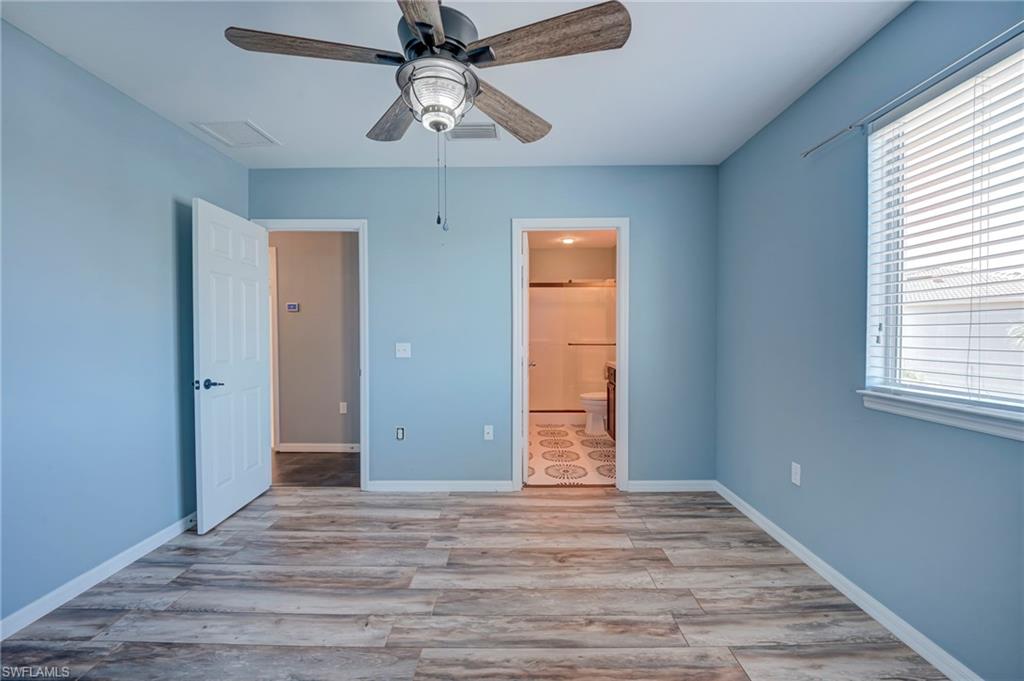 Unfurnished bedroom with light wood-style flooring, ensuite bath, and ceiling fan
