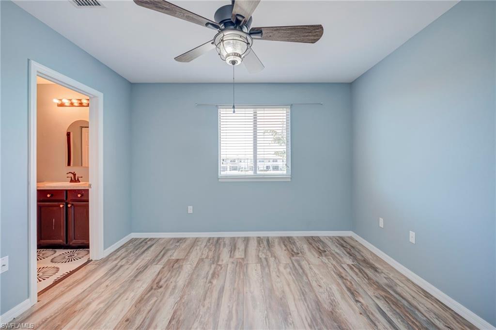 Unfurnished bedroom with light wood finished floors, connected bathroom, a ceiling fan, and arched walkways